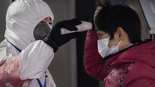 A Chinese health worker checks the temperature of a woman in Beijing, China. Picture: Kevin Frayer/Getty Images