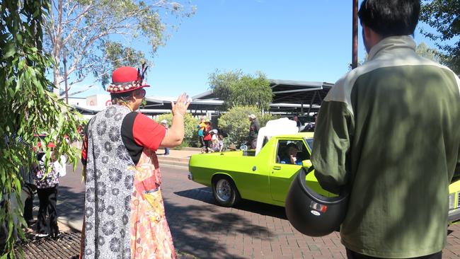 Alice Springs Town Crier Meredith Campbell waves to a passing car at the end of the parade.