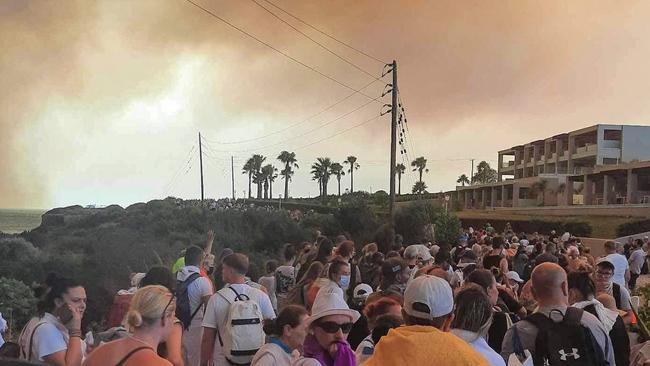 TOPSHOT - Tourists are evacuated from hotels during a wildfire on the Greek island of Rhodes on July 22, 2023. Three coastguard boats were leading more than 20 vessels in an emergency evacuation effort to rescue people from the Greek island, where fire has been raging out of control for five days. (Photo by STRINGER / Eurokinissi / AFP)