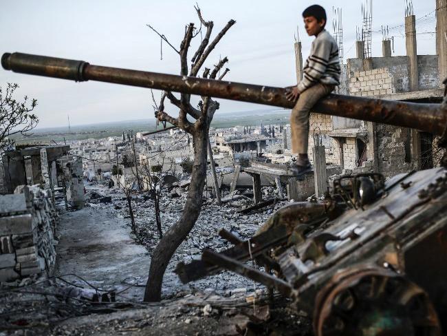 A Syrian Kurdish boy sits on a destroyed tank in the Syrian town of Kobane, also known as Ain al-Arab, on March 27, 2015. Islamic State (IS) fighters were driven out of Kobane on January 26 by Kurdish and allied forces. AFP PHOTO/YASIN AKGUL