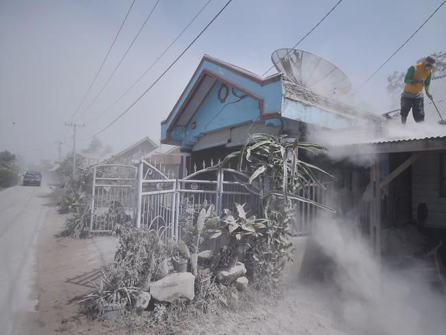 A man cleans dust from a roof of a house in Karo, North Sumatra. Picture: Lana Priatna / AFP