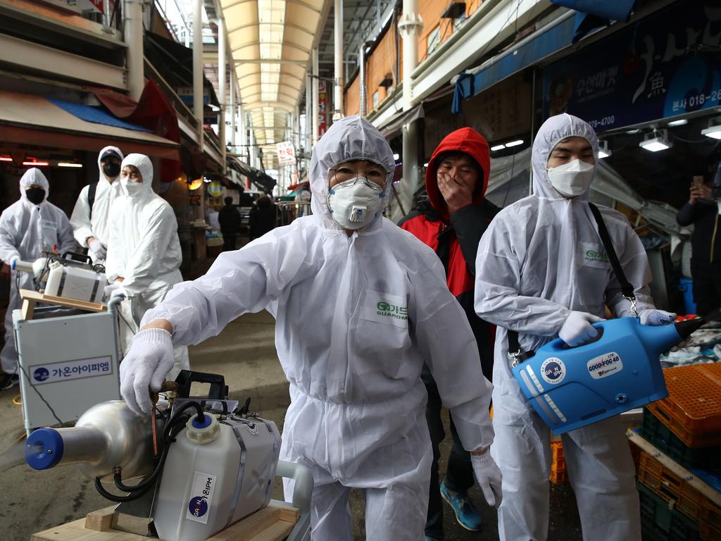 Disinfection professionals wearing protective gear spray antiseptic solution against the coronavirus at a traditional market in Seoul, South Korea. Picture: Getty Images