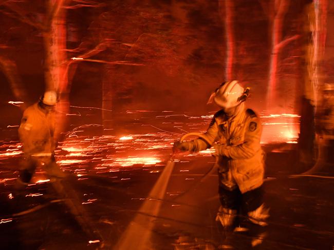 Firefighters hose down the area as they battle against bushfires around the town of Nowra in the Australian state of New South Wales on December 31, 2019. - Thousands of holidaymakers and locals were forced to flee to beaches in fire-ravaged southeast Australia on December 31, as blazes ripped through popular tourist areas leaving no escape by land. Picture: Saeed Khan/AFP
