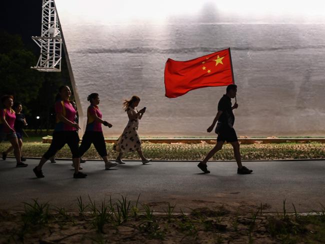 A man walks with the Chinese national flag in a park next to the Yangtze River in Wuhan, China's central Hubei province. Picture: Hector Retamal/AFP