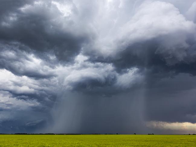 Rotating, threatening cumulonimbus storm clouds with rain-shaft over farmland. Horizontal, copy space.