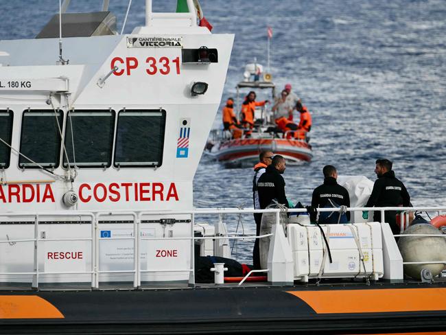 Italian Coast Guards carry a body on a rescue boat in Porticello harbour near Palermo, with a third body at the back of the boat. Picture: AFP