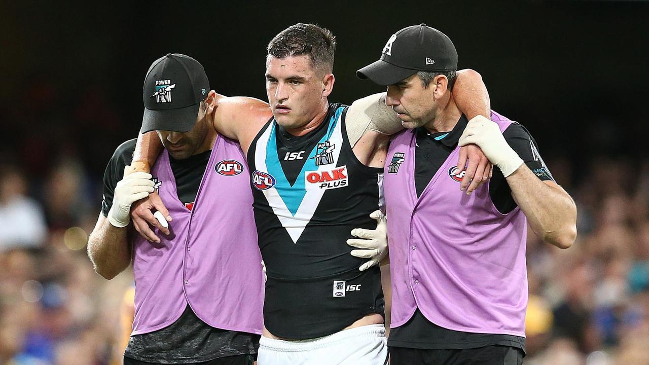 Port Adelaide's Tom Rockliff is helped off the ground after suffering a heavy knock