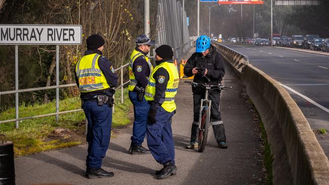 Police check a cyclist’s credentials in Albury-Wodonga on Wednesday, as motorists confronted long traffic jams at the NSW-Victoria border. Picture: Simon Dallinger