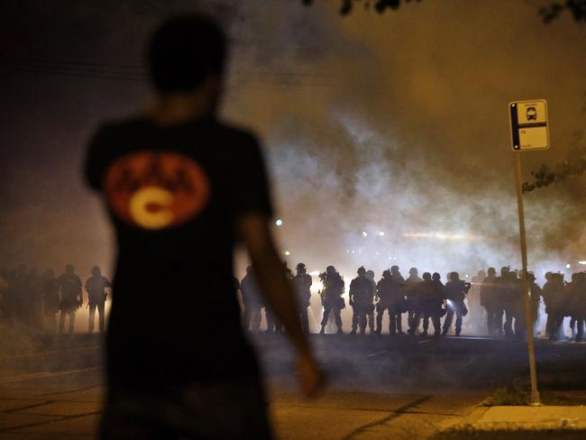 A man watches as police walk through a cloud of smoke during a clash with protesters on Wednesday night. AP Photo/Jeff Roberson