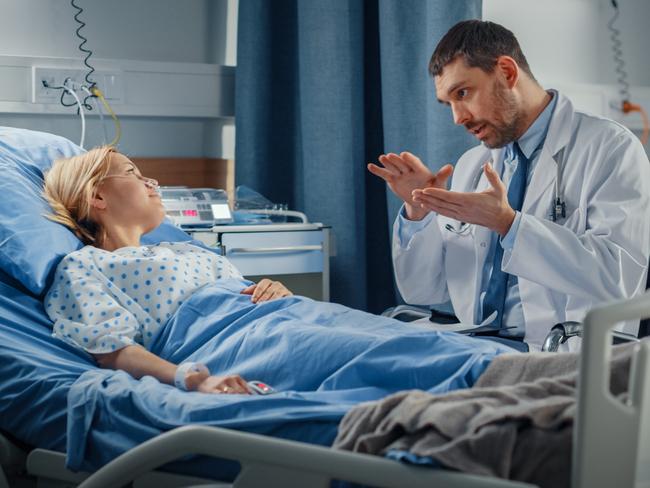 Hospital Ward: Friendly Doctor Talks to Smiling Young Woman Resting in Bed, Fully Recovering after Sickness. Physician Uses Tablet Computer, Does Checkup, Gives Treatment Advice, Health Recommendation