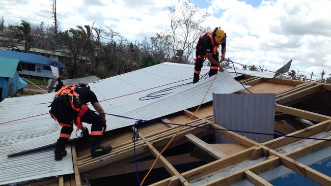 Rescuers repair a damaged roof on a school in Vanuatu following Cyclone Pam.