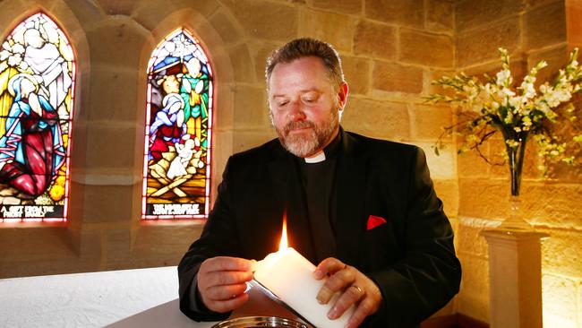 Father Rod lights a candle in St Mary’s historic Anglican Church, Gosford. Picture: Peter Clark