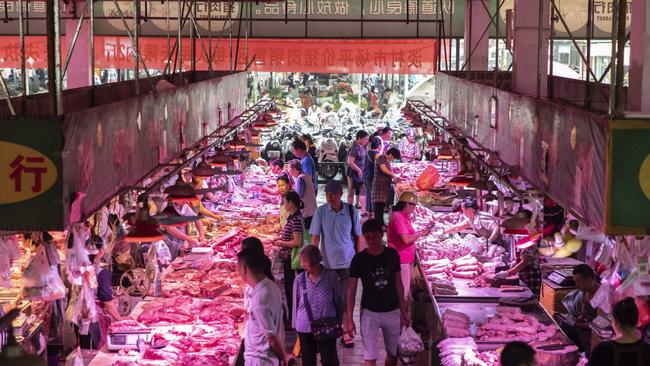 Customers walk past pork stalls at the Dancun Market in Nanning, Guangxi province, China.