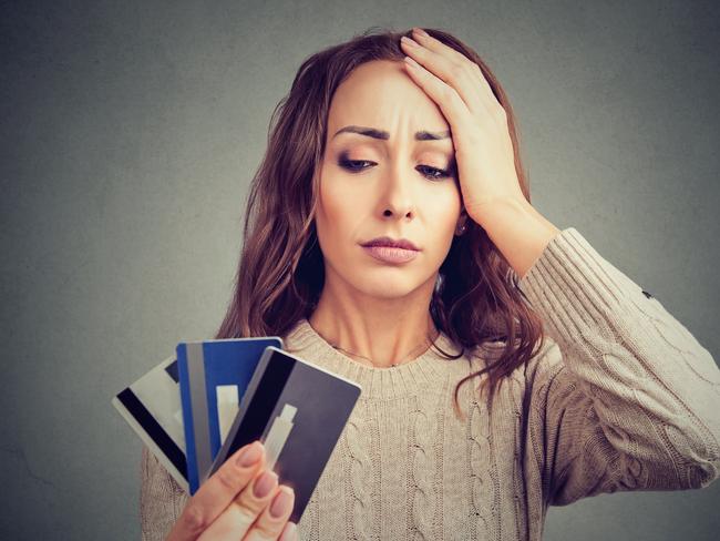 Young woman holding credit cards and looking stressed having financial problems.