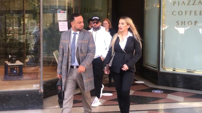 Kayla Attie (right) leaves Downing Centre Local Court supported by her alleged bikie partner (white hooded jumper) and lawyer Michael Moussa (left).