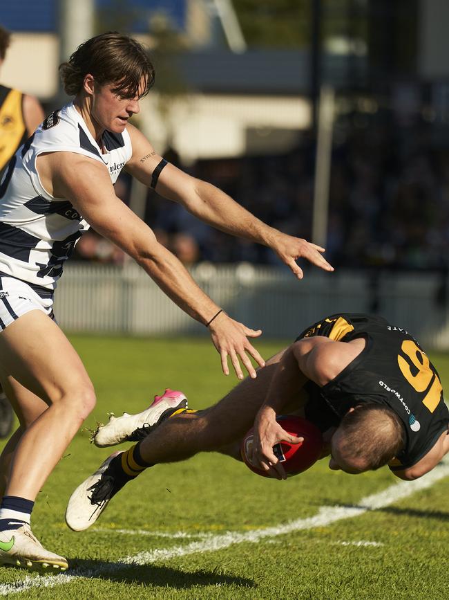 Glenelg’s Alex Martini takes a tumble under pressure from South Adelaide opponent Jye Menzie at the Bay. Picture: Matt Loxton.