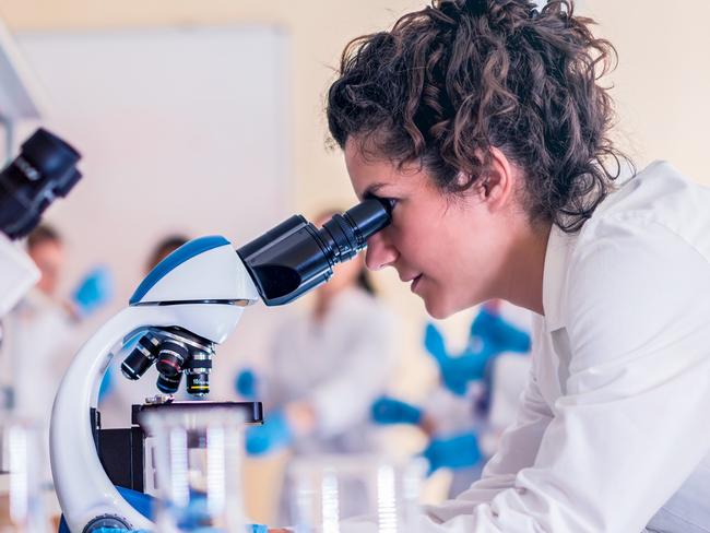 Scientist in lab doing research and using lab machines, test tubes, microscope and every laboratory equipment