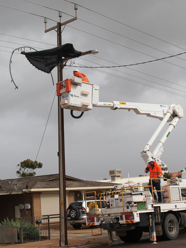 ETSA Utilities workers remove a shredded trampoline from a power pole in Collins Street, Ceduna. Picture: Andrew Brooks