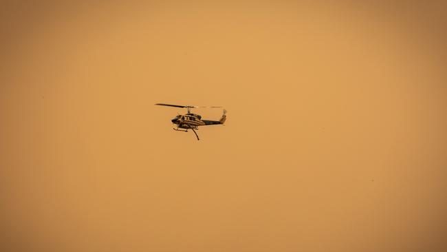 A firefighting helicopter flies over an evacuation centre. NCA NewsWire/Tony McDonough