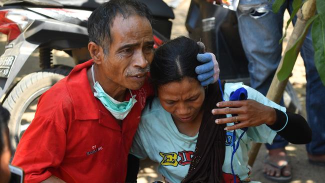 An Indonesian man (L) tries to calm a woman shortly after today’s aftershock hit the area in Tanjung on Lombok. Picture: Adek Berry/AFP