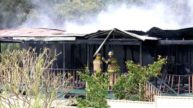 Firefighters inspect the gutted house on Russell Island. Picture: Steve Pohlner