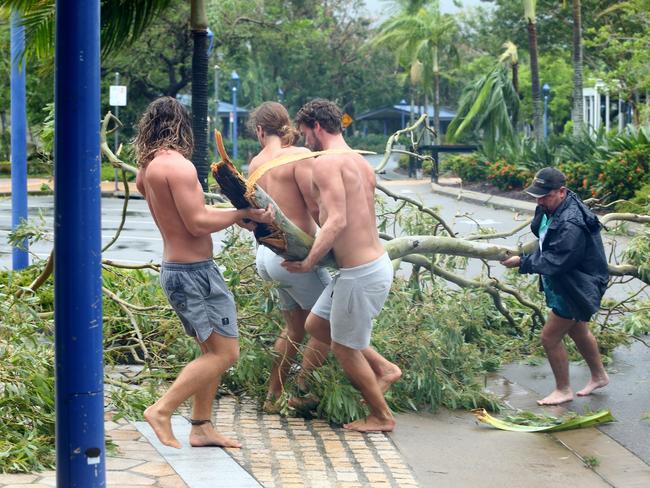 Locals Jayden Thacknay, 20; Raih Woodley, 22; and Rasa Lackey, 20; removing fallen branches from the main street of Airlie Beach as the eye of cyclone Debbie passed over. Photographer: Liam Kidston