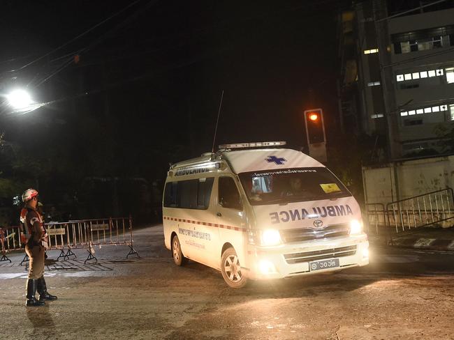 An ambulance leave the hospital, seen in the background at right, where the rescued boys where taken in Chiang Rai. Picture: Ye Aung Thu.