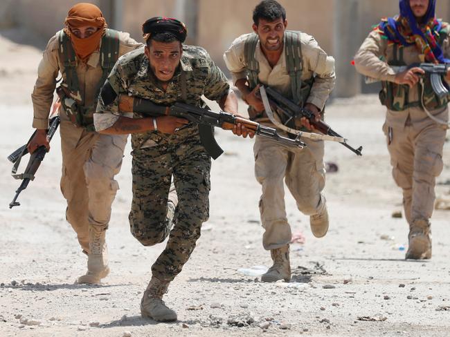 Kurdish fighters from the People's Protection Units (YPG) run across a street in Raqqa, Syria. Picture: Reuters