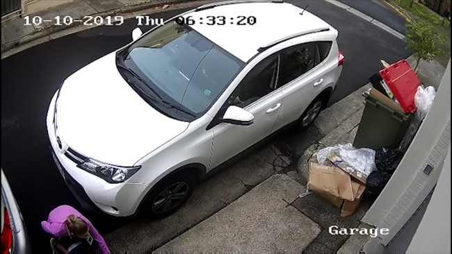 CCTV shows the woman crouching down between two parked cars to poop.