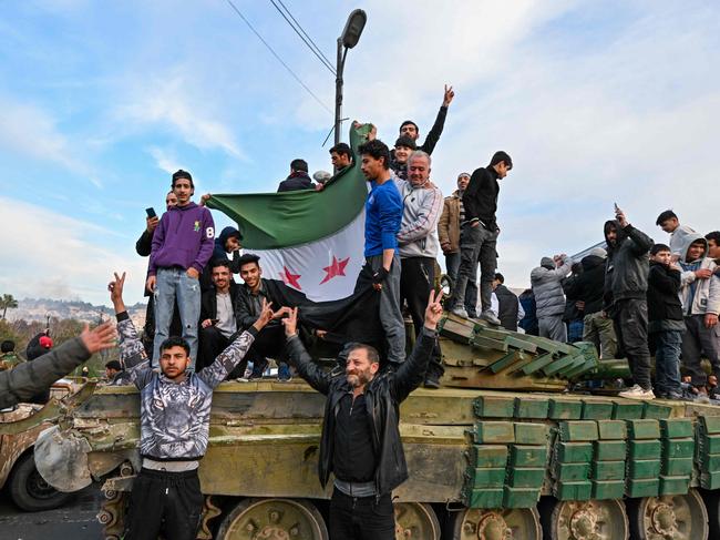 People celebrate with anti-government fighters at Umayyad Square in Damascus on December 8, 2024. Islamist-led rebels declared that they have taken Damascus in a lightning offensive on December 8, sending President Bashar al-Assad fleeing and ending five decades of Baath rule in Syria. (Photo by LOUAI BESHARA / AFP)