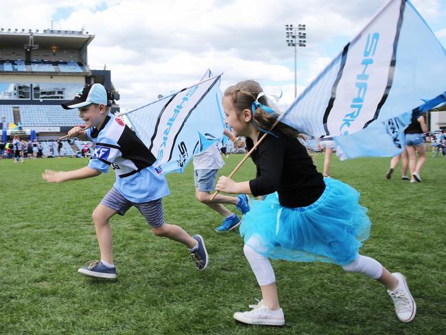 Young fans carrying flags have a race on the pitch. Picture: Stephen Cooper