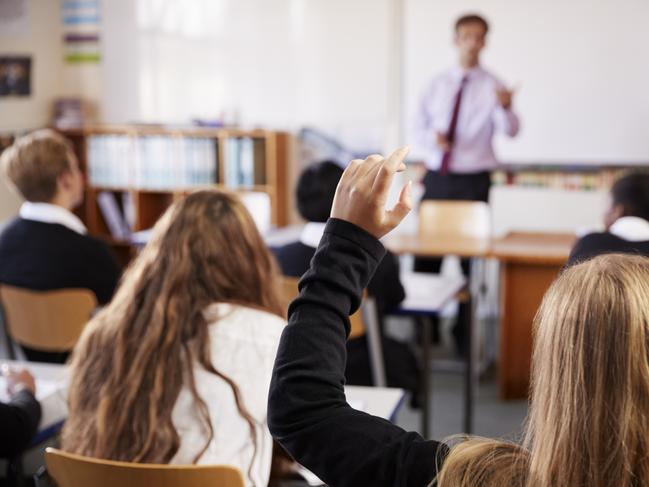 Female Student Raising Hand To Ask Question In Classroom