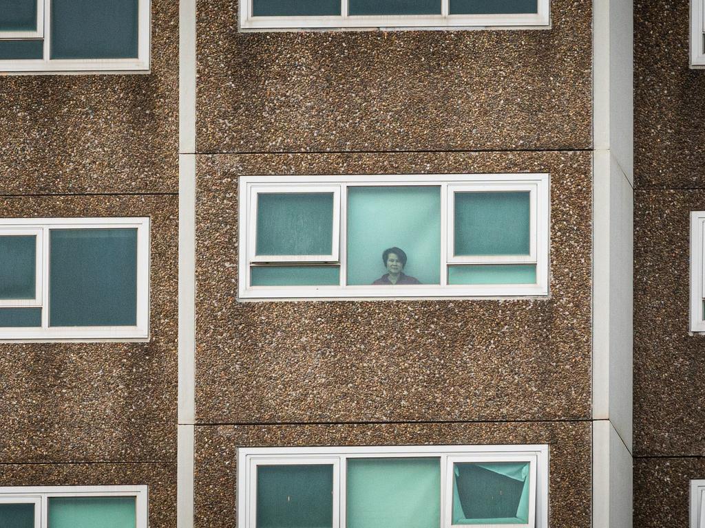 A lone woman looks out the window of her apartment at the North Melbourne public housing flats. Picture: Asanka Ratnayake/Getty Images