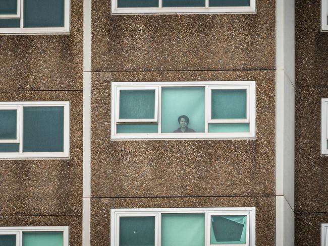 A lone woman looks out the window of her apartment at the North Melbourne public housing flats. Picture: Asanka Ratnayake/Getty Images