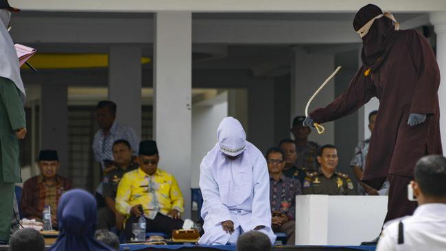 A woman is whipped in public by a member of the sharia police in Banda Aceh last month after being charged with breaking local Islamic law that outlaws public displays of affection. Picture: AFP