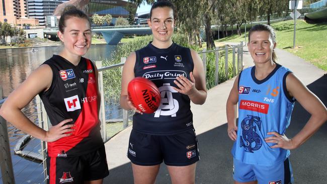 SANFLW players, from left, Madi Russell (West Adelaide), Brianna Cleggett (South Adelaide) and Kate Harris (Sturt) celebrate the introduction of a salary cap for the state league women’s competition. Picture: Dean Martin