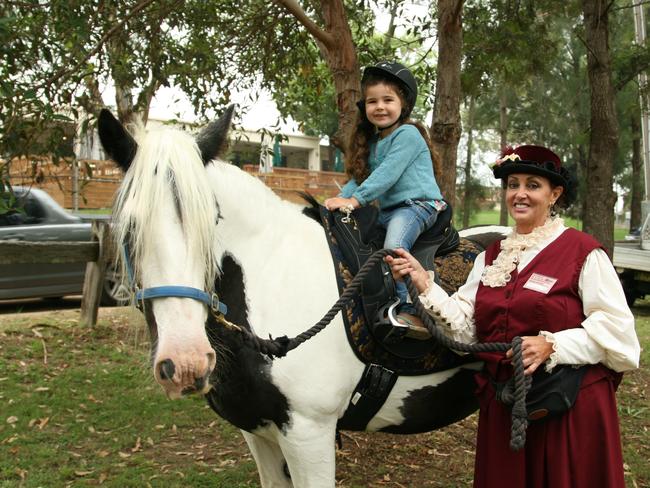 Sophie Tuck, 4, from Richmond with horse handler Catherine and a Gypsie Cobb horse at The Australiana Pioneer Village, Wilberforce on Australia Day in 2015.