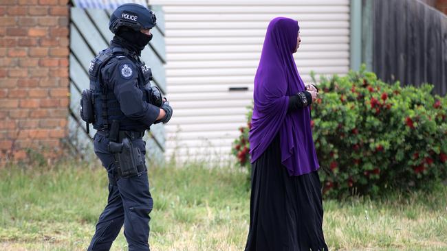 An officer turns a woman from the site of the raid. Picture: Sarah Matray