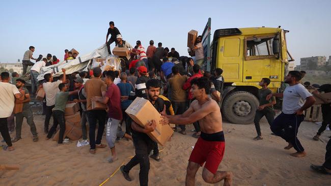 Palestinians carry boxes of humanitarian aid after rushing the trucks transporting the international aid from the US-built Trident Pier near Nuseirat in the central Gaza Strip on May 18. Picture: AFP