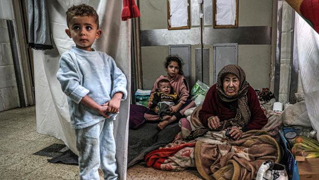 An elderly woman looks on as she sits with children at a makeshift camp in an area of the European Hospital in Khan Yunis in the southern Gaza Strip on December 31, 2023. Picture: AF