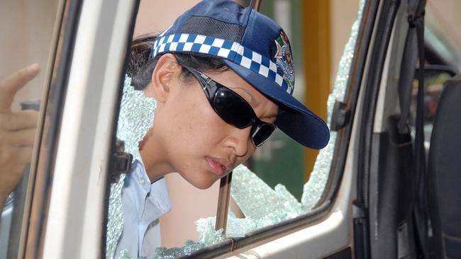 Police officer Constable Michelle Rizal inspects damage to a police car.