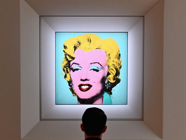 (FILES) In this file photo taken on April 29, 2022 a man looks at Andy Warhol's 'Shot Sage Blue Marilyn' during Christie's 20th and 21st Century Art press preview at Christie's New York in New York City. - An iconic portrait of Marilyn Monroe by American pop art visionary Andy Warhol went under the hammer for a record $195 million on May 9, 2022 at Christie's, becoming the most expensive 20th century artwork ever sold at public auction. "Shot Sage Blue Marilyn," produced in 1964 two years after the death of the glamourous Hollywood star, sold for exactly $195.04 million, including fees, in just four minutes in a crowded room at Christie's headquarters in Manhattan. (Photo by Angela Weiss / AFP)