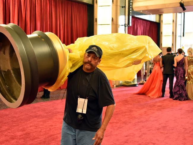 A worker carries an Oscar statue on the red carpet outside Dolby Theatre as preparations are underway for the 87th annual Academy Awards in Hollywood, California.