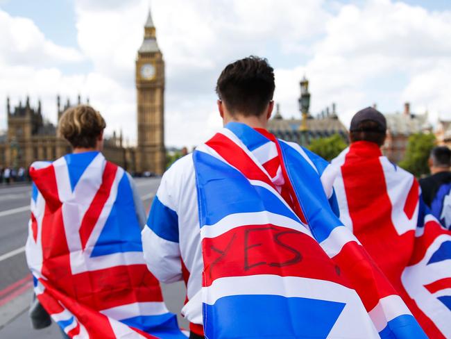 TOPSHOT - People walk over Westminster Bridge wrapped in Union flags, towards the Queen Elizabeth Tower (Big Ben) and The Houses of Parliament in central London on June 26, 2016. Britain's opposition Labour party plunged into turmoil Sunday and the prospect of Scottish independence drew closer, ahead of a showdown with EU leaders over the country's seismic vote to leave the bloc. Two days after Prime Minister David Cameron resigned over his failure to keep Britain in the European Union, Labour leader Jeremy Corbyn faced a revolt by his lawmakers who called for him, too, to quit. / AFP PHOTO / Odd ANDERSEN