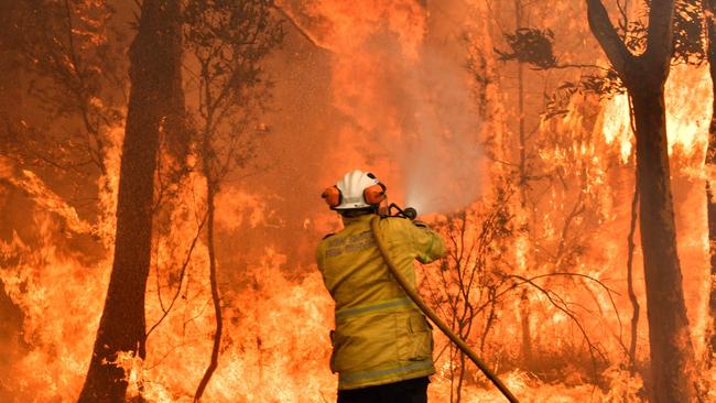 This file photo taken on December 10, 2019 shows a firefighter conducting back-burning measures to secure residential areas from encroaching bushfires in the Central Coast, some 90-110 kilometres north of Sydney. - Climate change is already buffeting Australia with more extreme bushfires, droughts and cyclones -- and the fossil-fuel reliant country should brace for worse to come, according to Australia's top science and weather agencies on November 13, 2020. (Photo by Saeed KHAN / AFP)