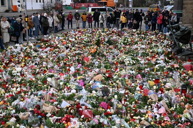 Mourners gather at a makeshift memorial for the victims of a car-ramming attack on a Christmas market in Germany