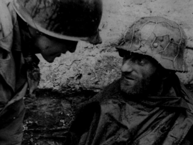 A US First Army soldier talks with a dirty, battle-weary German prisoner captured during the bitter four week fight for Hurtgen, Germany in 1944.