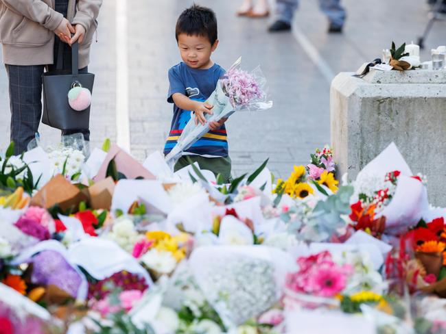 A young child leaves a bunch of flowers to the ever-growing tribute. Picture: David Swift