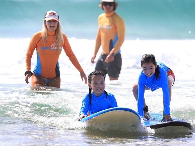 Chinese tourists including Zhou Zi Yan, 7, and Cai Queen, 9, from Shanghai, enjoy learn-to-surf classes at the Spit on the Gold Coast with Get Wet Surf School. Picture: Adam Head