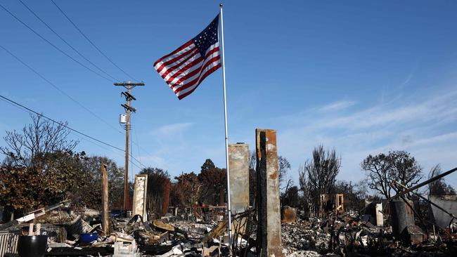 An American flag flies above the remains of a home which burned in the Palisades Fire on January 28, 2025 in Pacific Palisades, California. Photo by MARIO TAMA / GETTY IMAGES NORTH AMERICA / Getty Images via AFP)